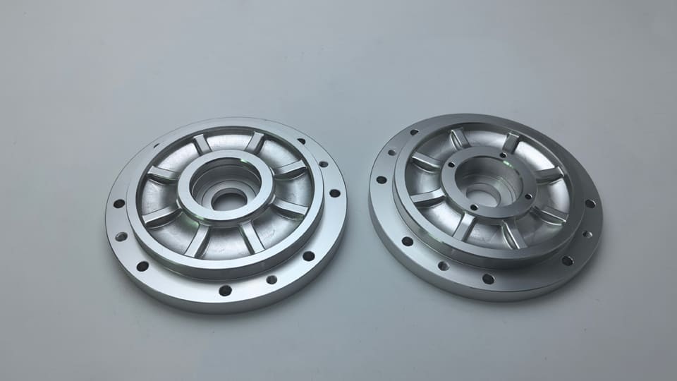 Two round flanged housings with central bores and machined face features